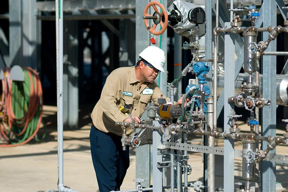 Operator wearing safety gear checking valves and gauges on a hydrogen plant